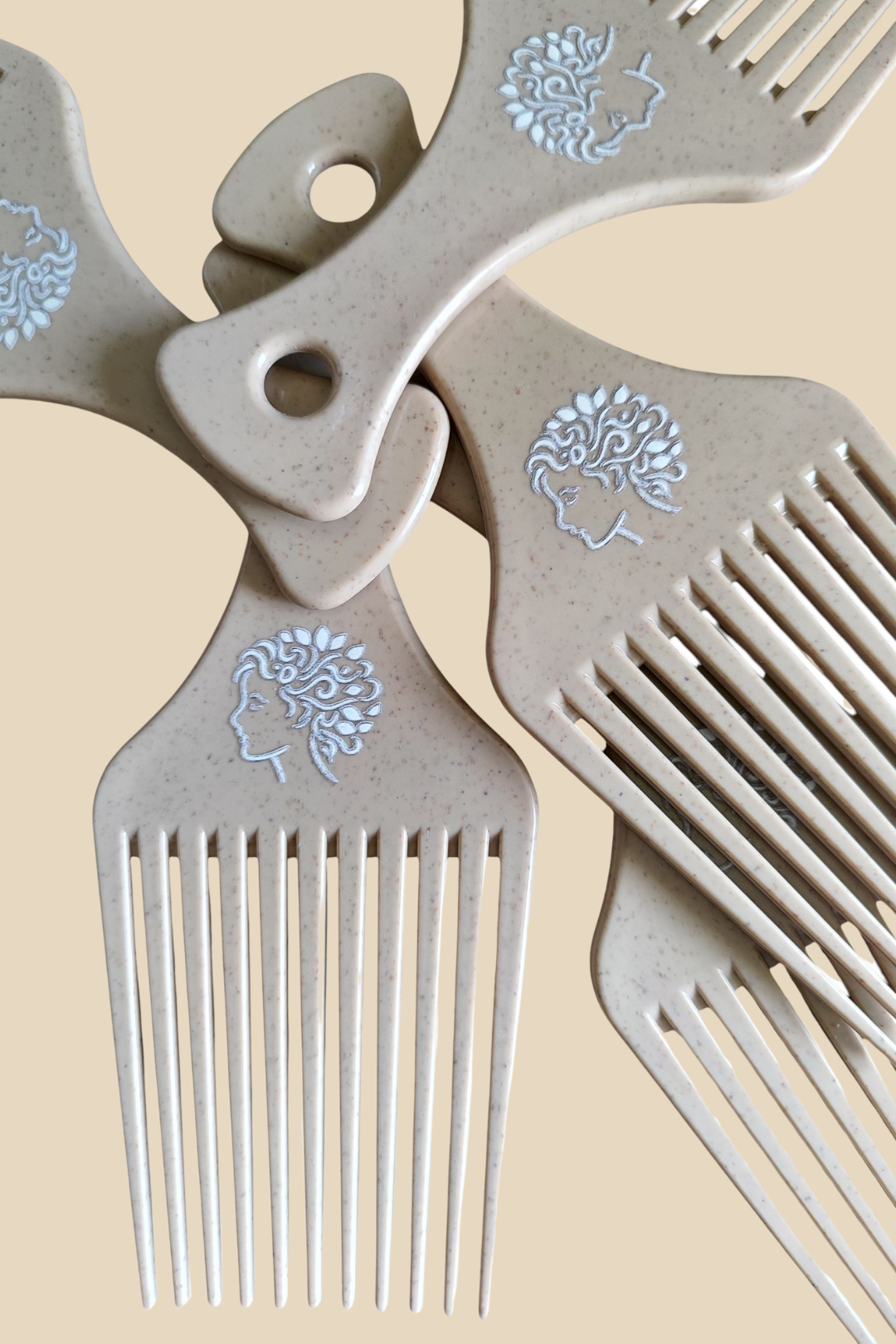Peignes afro beige en plastique recyclé avec logo Ikala Ngita gravé, disposés en éventail sur fond beige