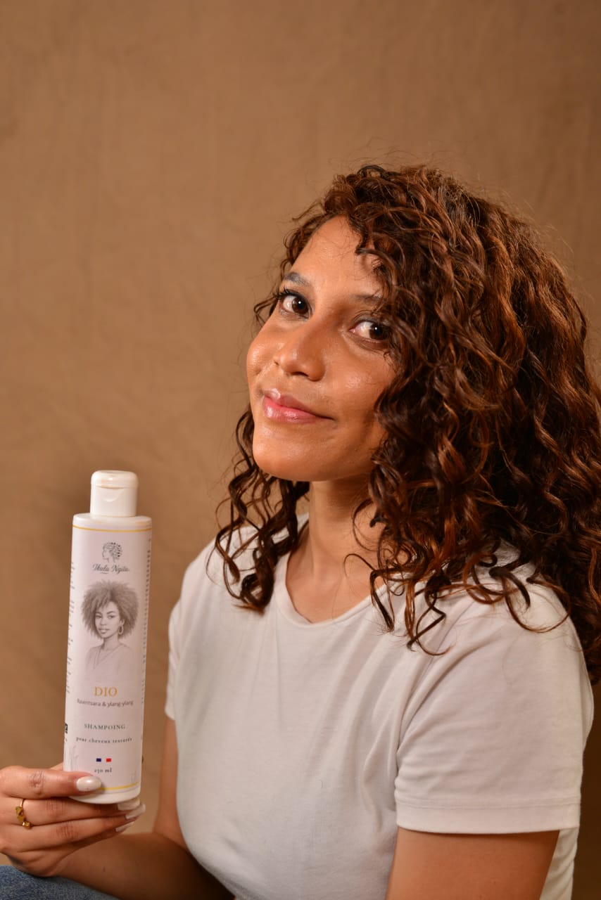 Shampoing doux Dio Ikala Ngita présenté sur cheveux bouclés naturels pour nettoyer et hydrater les cheveux texturés.