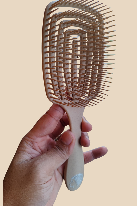 Main tenant une brosse démêlante beige à picots souples