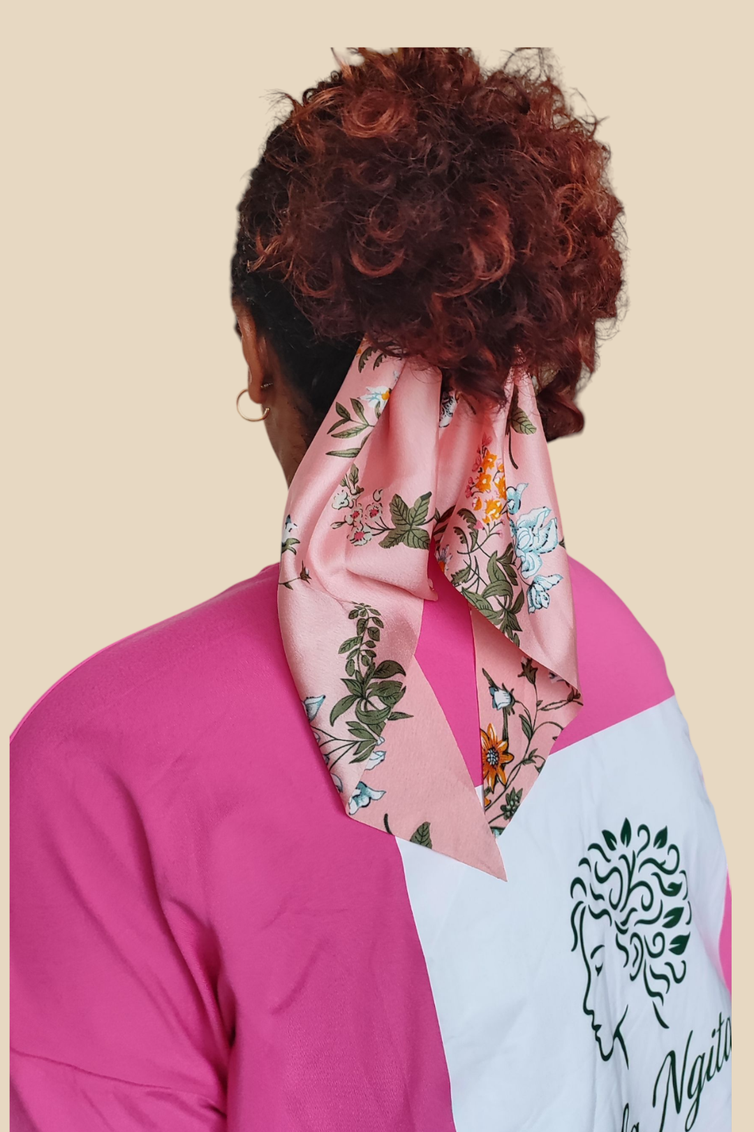 T-shirt rose Ikala Ngita – Vue de dos avec logo vert sapin sur fond blanc, coiffure attachée avec foulchie rose à motifs fleuris